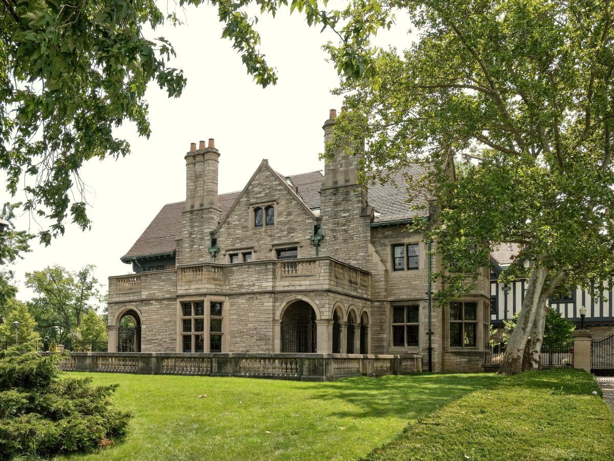 Stone manor house with slate roof, tall chimneys and a balustraded terrace