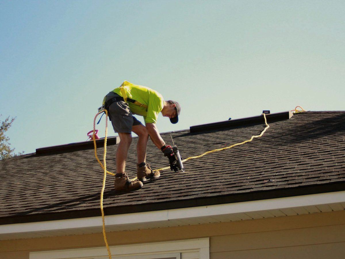 Roofer fastening shingles during a residential roof replacement